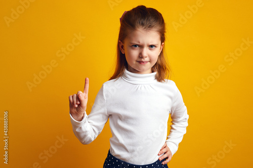 Displeased young girl waving index finger in no and prohibition gesture photo