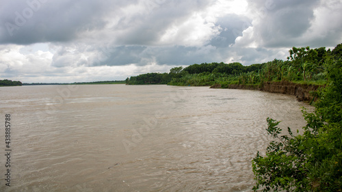 The landscape of Bangladesh next to a beautiful river. Cloudy skies in the midday sun. It is the river Gorai  Madhumati .