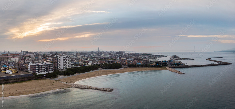 Apartment buildings and sprawling city along coastal beach and port at sunrise