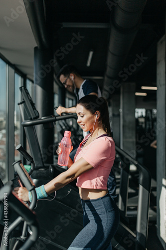 Young fit man and woman running on treadmill in modern fitness gym.