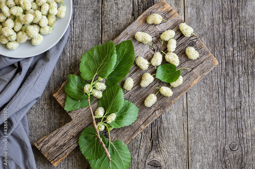 Fresh white mulberries in plate with branch on wooden background, summer fruit concept Fresh white mulberries in plate with branch on wooden background, summer fruit concept