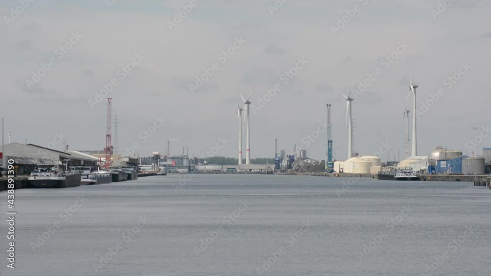 Dok in the harbour of Ghent, Flanders, Belgium, with industrial buildings and silo`s and windmills on a cloudy day Dok in the harbour of Ghent, Flanders, Belgium, with industrial buildings and silo`s and windmills on a cloudy day