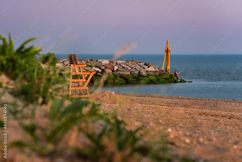 A morning view of Cedar beach, Mt Sinai, NY, in the morning with iconic stone wall and wood light tower. A morning view of Cedar beach, Mt Sinai, NY, in the morning with iconic stone wall and wood light tower.