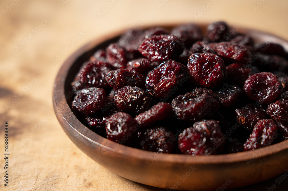 Dried cranberries in a wooden bowl on a wooden background. Dried cranberries in a wooden bowl on a wooden background.