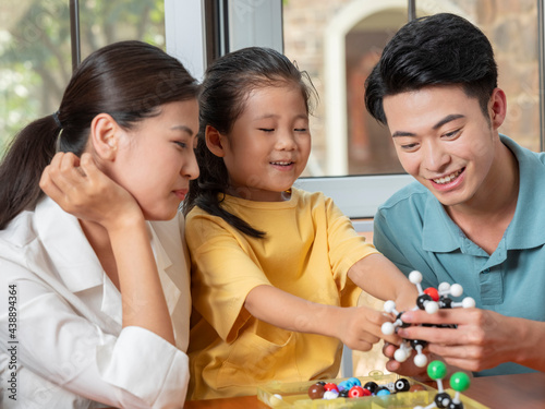 Happy family of three doing molecular structure model together