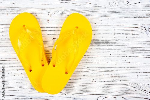 yellow rubber slippers on a white wooden background, view from above, place under the text