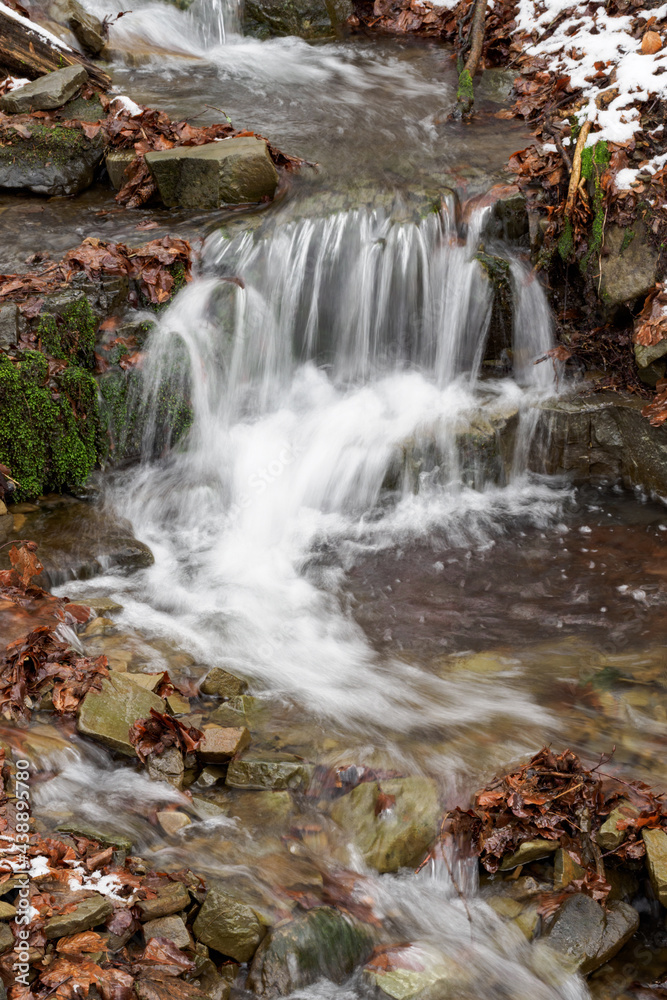 Water flowing in the river between the stones in winter.
