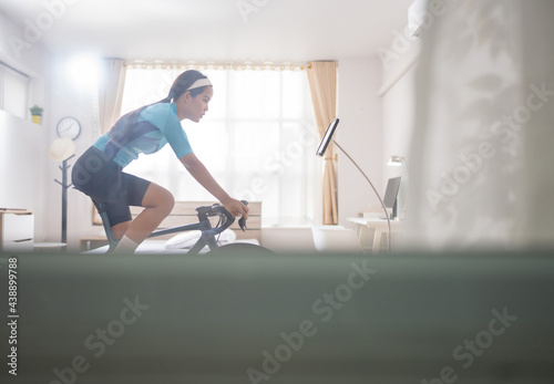 Asian woman Riding a bike online trainer in the bedroom