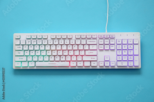 Modern RGB keyboard on turquoise background, top view photo