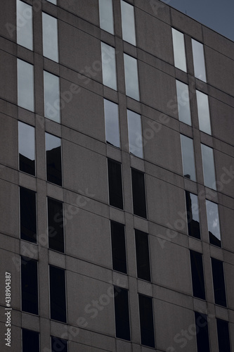A concrete building with glass reflecting the sky.