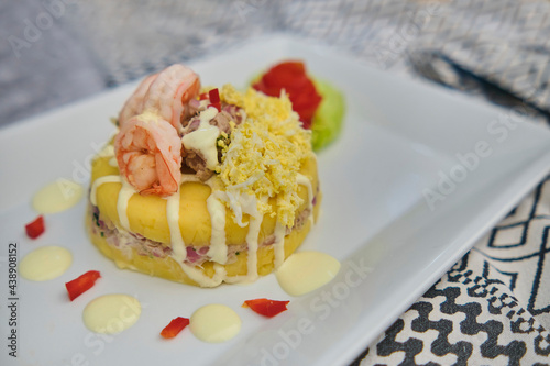 Peruvian Food: Causa rellena de atun. Tuna causa rellena. Traditional peruvian dish from yellow potato, tuna, avocado on white plate. Selective focus photo