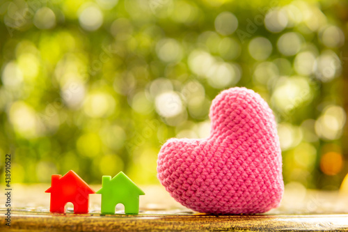 Hand are hold rainbow heart and home model.Give love to the family for happiness..Have background in garden and light of sun.