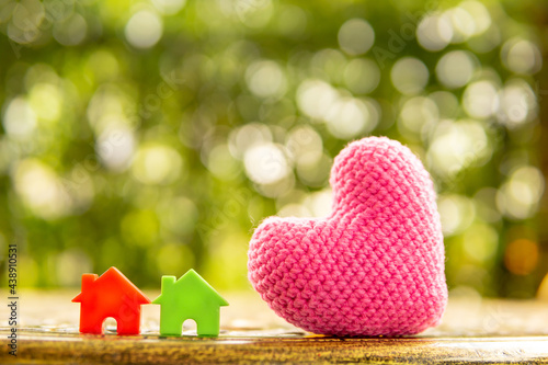 Hand are hold rainbow heart and home model.Give love to the family for happiness..Have background in garden and light of sun.