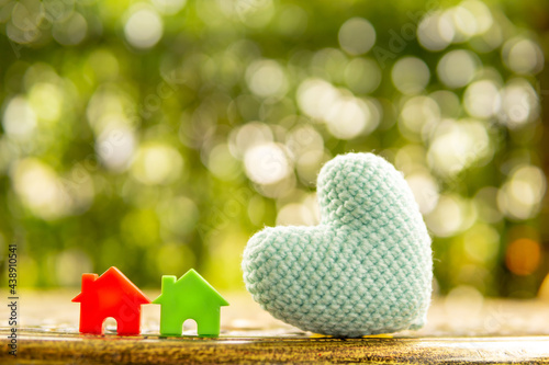 Hand are hold rainbow heart and home model.Give love to the family for happiness..Have background in garden and light of sun.