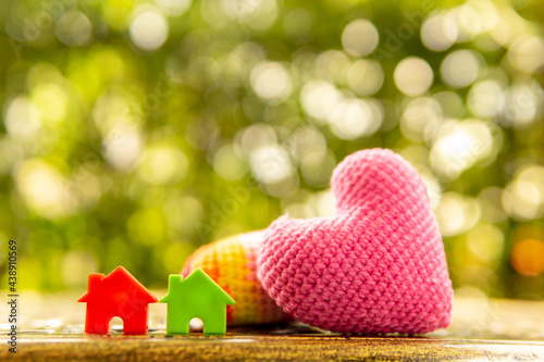 Hand are hold rainbow heart and home model.Give love to the family for happiness..Have background in garden and light of sun.
