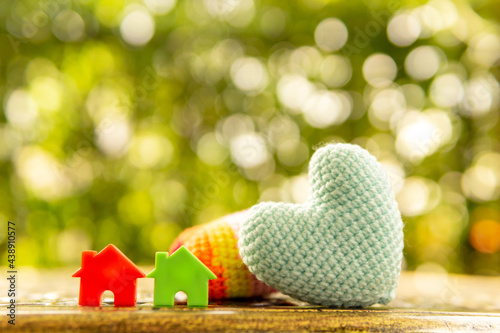 Hand are hold rainbow heart and home model.Give love to the family for happiness..Have background in garden and light of sun.