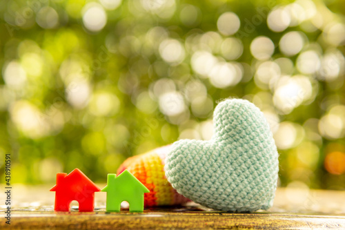 Hand are hold rainbow heart and home model.Give love to the family for happiness..Have background in garden and light of sun.