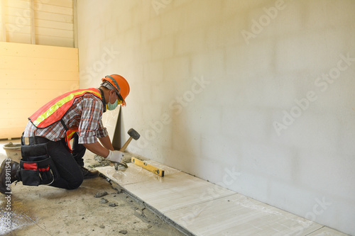 Laying Ceramic Tiles.Home tile improvement - handyman with level.Tiler works with flooring