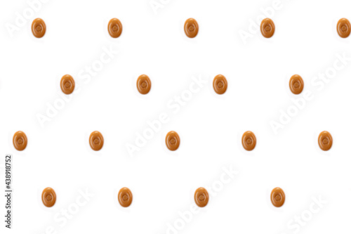 A pattern of oval caramel candies on a white background.