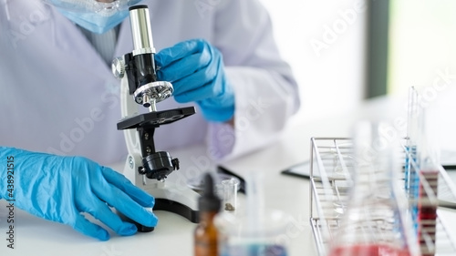 Young Asian scientist Working looking through a microscope doing research for analyzing a Experiments sample in a forensic laboratory.