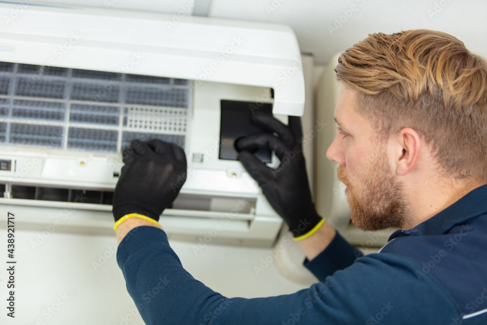 a professional electrician man is fixing the heavy air conditioner