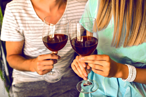 Close up details of romantic evening of pretty couple drinking red wine end enjoying time together, modern interior and trendy elegant clothes.