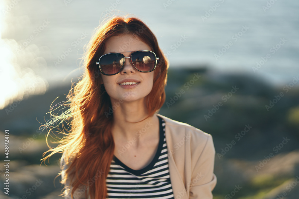 woman in the mountains in summer at sunset near the sea and glasses on her face