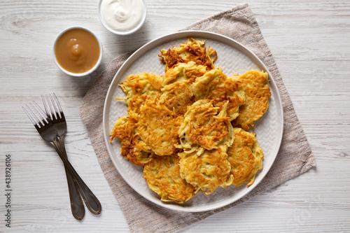 Homemade Potato Pancakes Latkes with Apple Sauce and Sour Cream on a white wooden background, top view. Flat lay, overhead, from above.