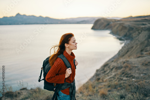 woman tourist in a sweater with a backpack in the mountains near the sea side view