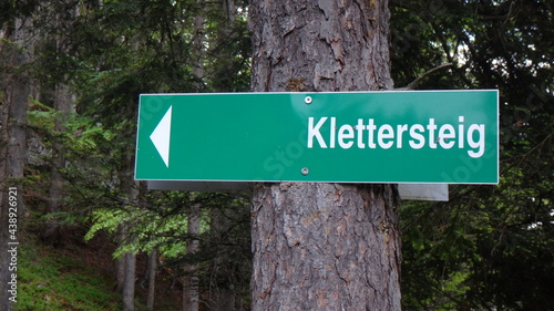 Green direction sign to Klettersteig in forest, via ferrata Austria photo