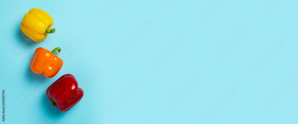 Three fresh bright sweet peppers on a blue background. Top view, flat lay. Banner Three fresh bright sweet peppers on a blue background. Top view, flat lay. Banner