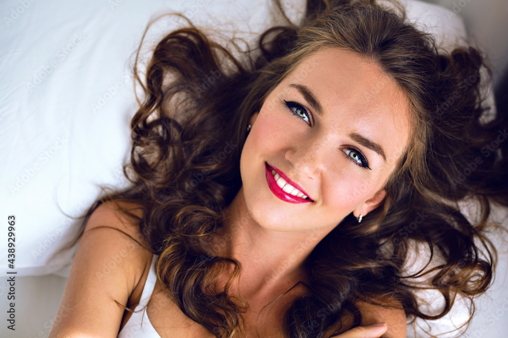 Tender fashion morning portrait of stunning young sexy woman with freckles fluffy hairs and bright make up, lay and relax on the bed, cute smiling positive face and emotions, soft colors. Tender fashion morning portrait of stunning young sexy woman with freckles fluffy hairs and bright make up, lay and relax on the bed, cute smiling positive face and emotions, soft colors.