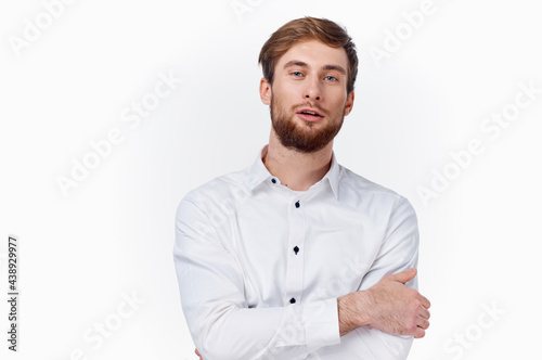 a young man in a white shirt hugs himself with his hands on a light background front view © SHOTPRIME STUDIO