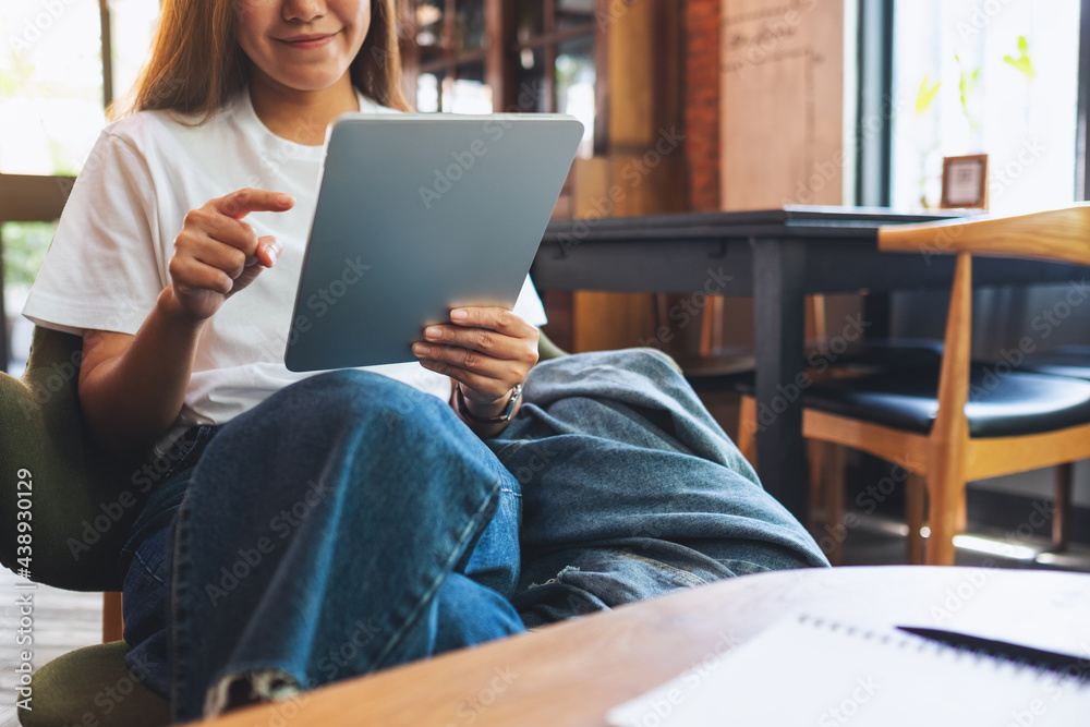 A beautiful young asian woman holding and using digital tablet in cafe A beautiful young asian woman holding and using digital tablet in cafe