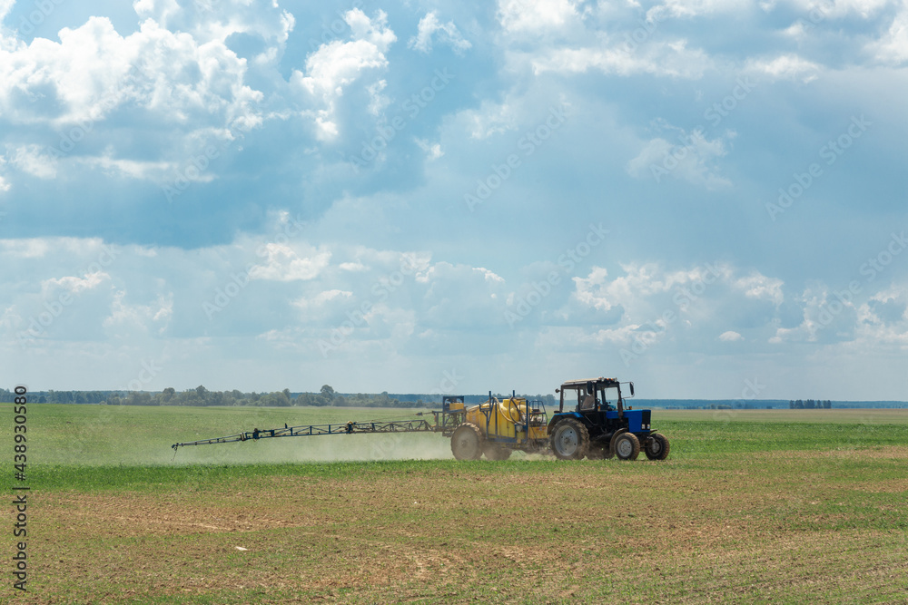 Fototapeta premium Tractor sprays liquid chemical fertilizers