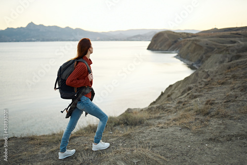 woman resting in the mountains outdoors near the sea and backpack on her back tourism model