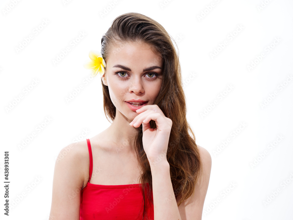 pretty brunette woman in a red t-shirt with a yellow flower in her hair touches her face with her hand pretty brunette woman in a red t-shirt with a yellow flower in her hair touches her face with her hand