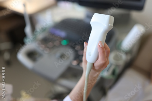 Doctor holding ultrasound probe in his hand in clinic closeup