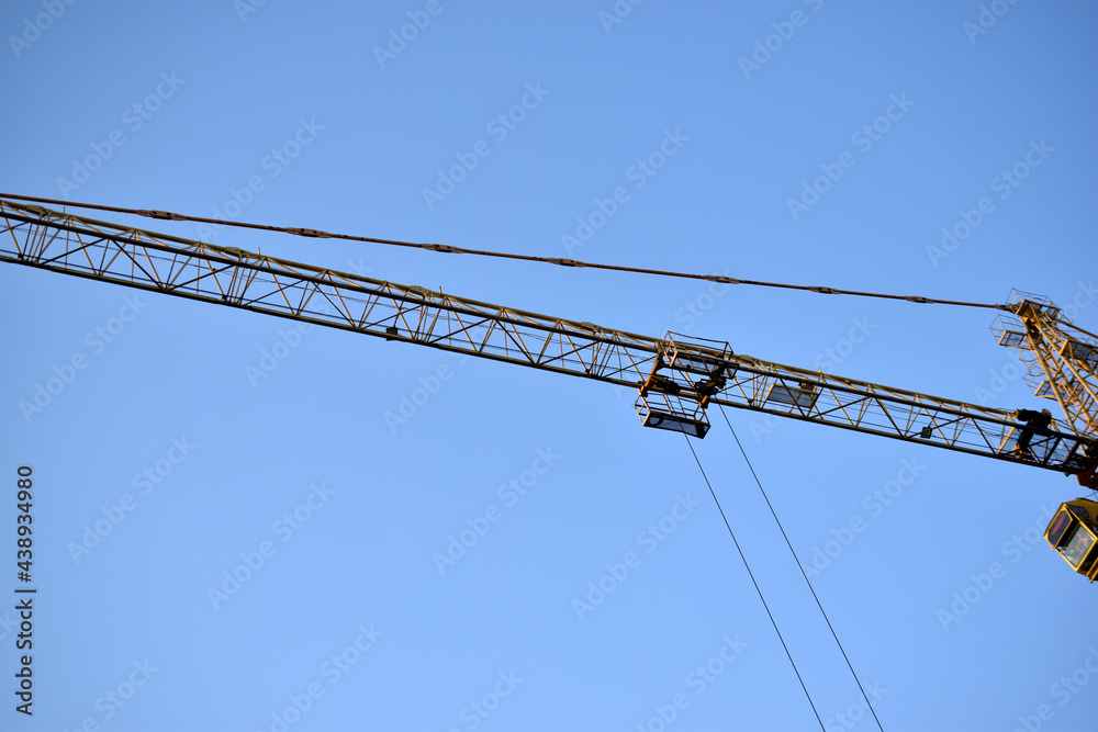 Yellow tower crane its boom is a building under construction