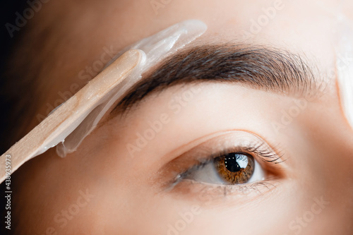 Closeup Master wax depilation of eyebrow hair in women, brow correction photo