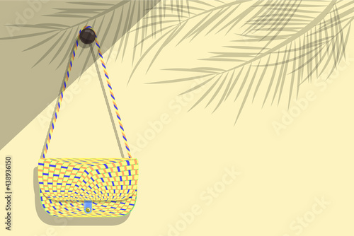Women's weave pattern shoulder bag was hung on a light brown wall where sunlight poured into the room against the shadow of the coconut leaves concept of summer travel trip