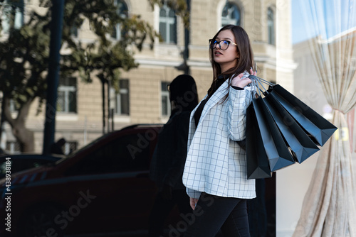 Stylish woman shopper with black bags. Beautiful girl near a fashion store. Black friday concept