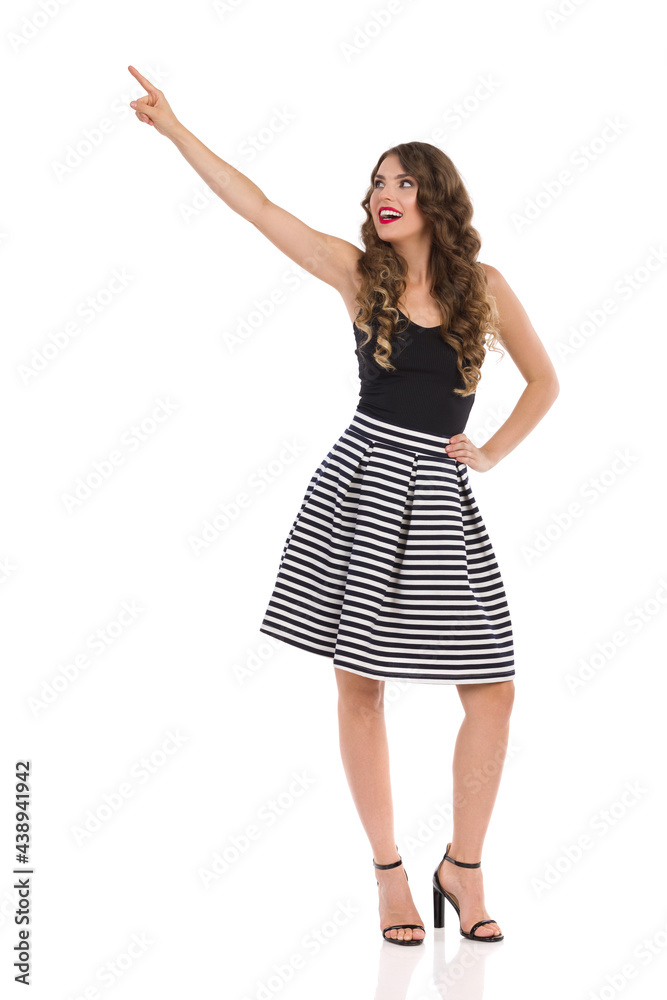 Young Woman In Striped Mini Skirt And High Heels Is Pushing Something With Index Finger. Young Woman In Striped Mini Skirt And High Heels Is Pushing Something With Index Finger.