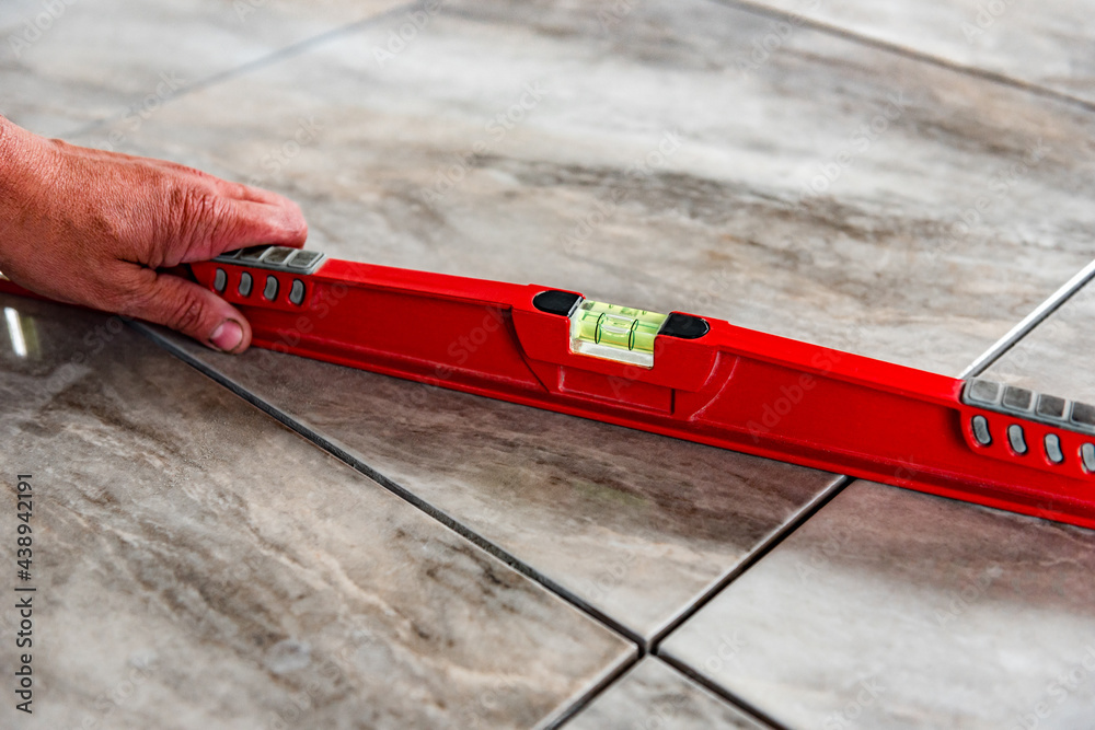 Worker checks the level of the tile floor.