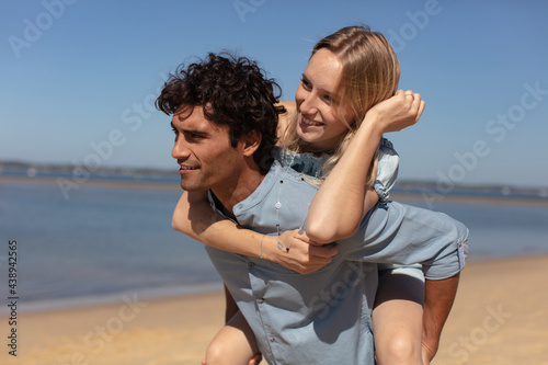guy carrying girlfriend on his back at the beach