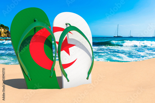Flip flops with Algerian flag on the beach. Algeria resorts, vacation, tours, travel packages concept. 3D rendering