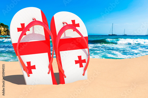 Flip flops with Georgian flag on the beach. Georgia resorts, vacation, tours, travel packages concept. 3D rendering