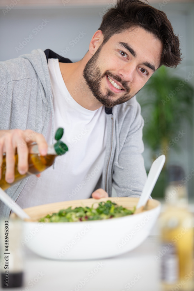 young man in casual preparing vegetarian salad young man in casual preparing vegetarian salad