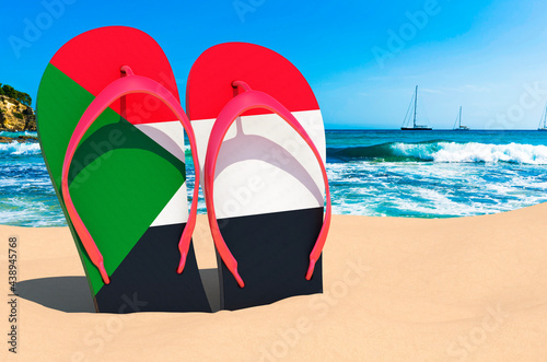 Flip flops with Sudanese flag on the beach. Sudan resorts, vacation, tours, travel packages concept. 3D rendering
