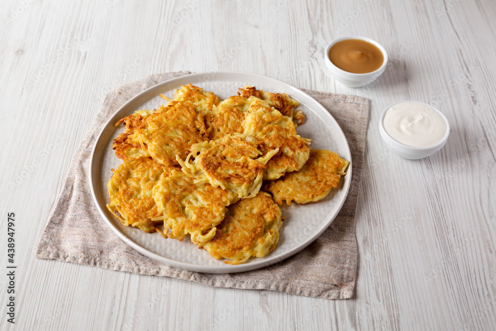 Homemade Potato Pancakes Latkes with Apple Sauce and Sour Cream on a white wooden background, low angle view.